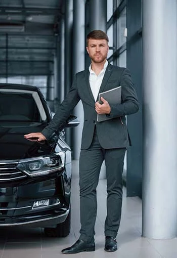A Star Limousine executive confidently standing in front of a chauffeur-driven luxury vehicle